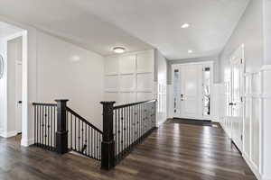 Entrance foyer featuring dark wood-type flooring, a decorative wall, wainscoting, and recessed lighting