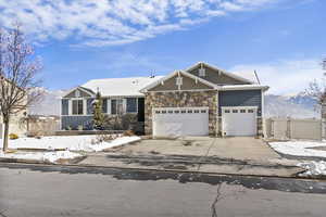 Craftsman-style house with concrete driveway, stone siding, a garage, a mountain view, and a gate