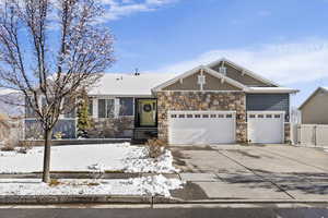 View of front of home featuring concrete driveway, an attached garage, stone siding, and a gate