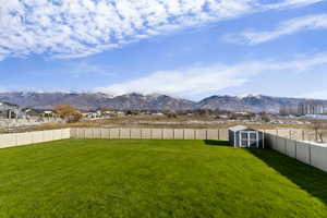 Fenced backyard featuring a shed and a mountain view