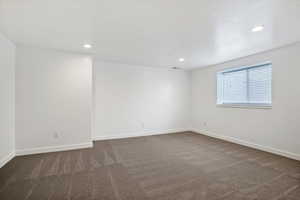 Spare room featuring dark colored carpet and recessed lighting