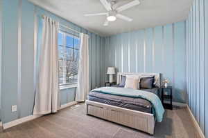 Bedroom with ceiling fan, carpet flooring, and wallpapered walls
