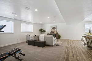 Living area with a textured ceiling, light wood-style flooring, and recessed lighting