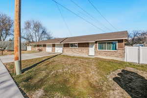 Ranch-style home with brick siding, driveway, roof with shingles, and a gate