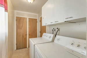 Laundry room with cabinet space, washer and dryer, and light tile patterned floors 890