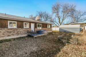 Rear view of property with brick siding, an outdoor structure, roof with shingles, and a chimney 890