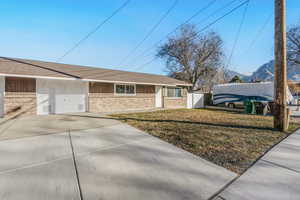 Ranch-style home featuring brick siding, roof with shingles, and concrete driveway 880