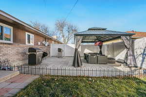 Fenced backyard with an outdoor hangout area, a patio, a gazebo, and area for grilling 880