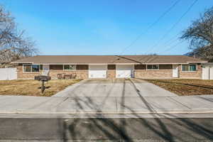 Ranch-style house featuring driveway, brick siding, an attached garage, and a shingled roof