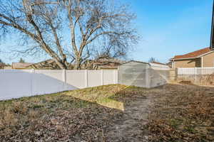 Fenced backyard featuring a storage shed 880