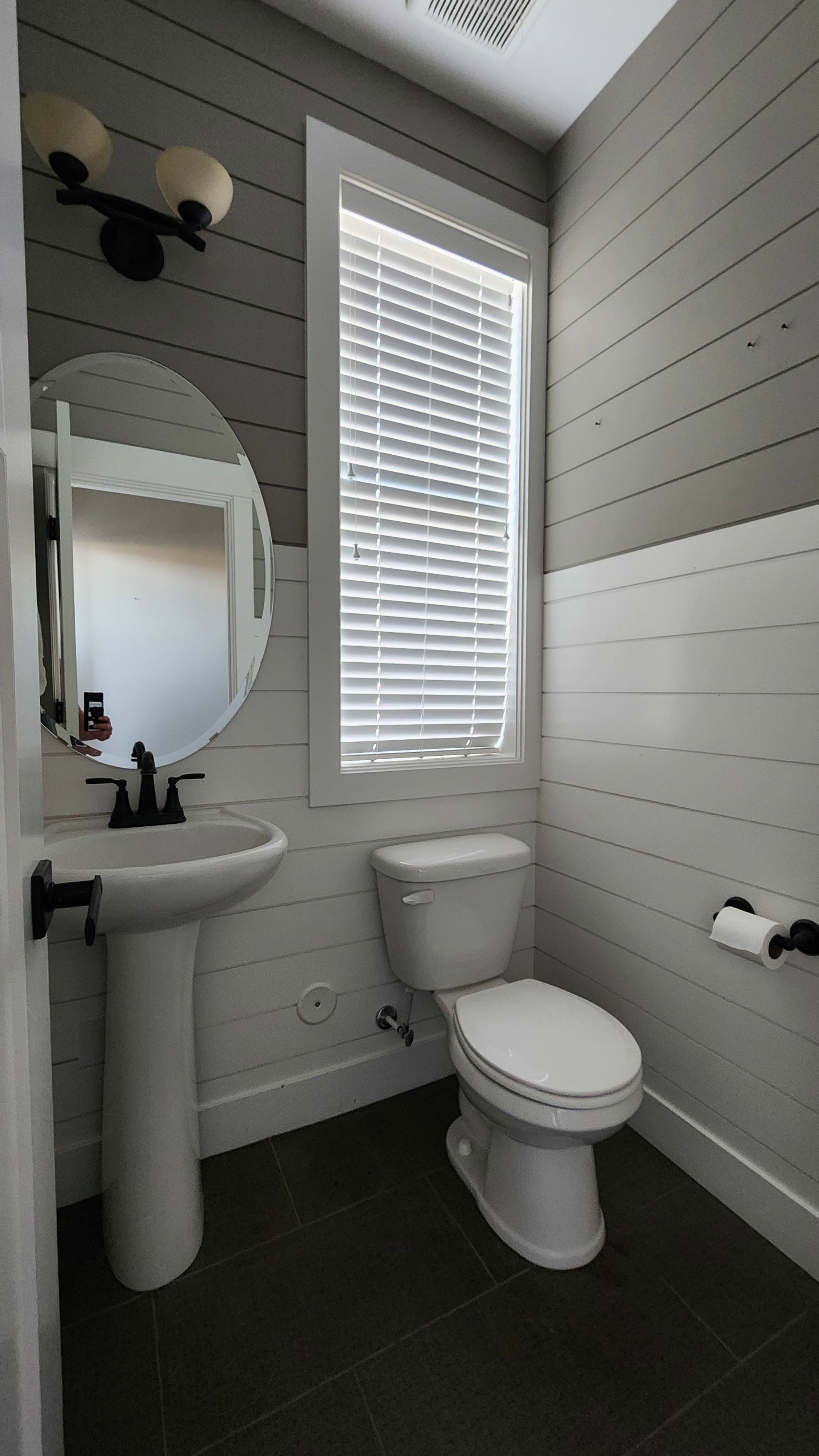 Bathroom featuring dark tile patterned flooring and wood walls
