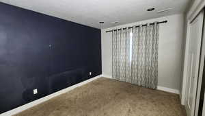 Empty room featuring carpet and a textured ceiling