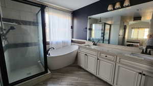 Bathroom with a shower stall, a soaking tub, double vanity, and healthy amount of natural light