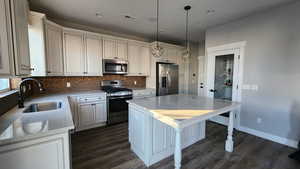 Kitchen featuring stainless steel appliances, pendant lighting, light stone countertops, tasteful backsplash, and dark wood finished floors