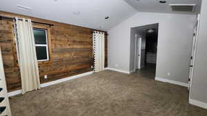 Spare room featuring wood walls and carpet