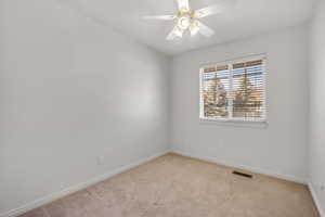 Carpeted spare room featuring a ceiling fan and baseboards