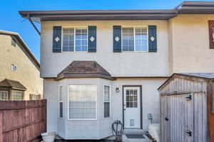 View of front of home featuring stucco siding and a shed