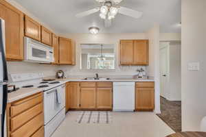 Kitchen featuring white appliances, light countertops, light flooring, and a ceiling fan