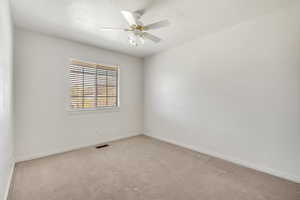 Carpeted spare room with a ceiling fan and a textured ceiling