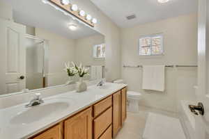 Bathroom with a shower stall, double vanity, plenty of natural light, and light flooring