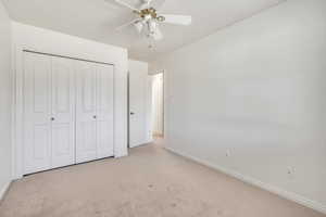 Unfurnished bedroom featuring carpet, a ceiling fan, and a closet