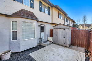 Back of property featuring a storage shed, stucco siding, a patio, and a fenced backyard