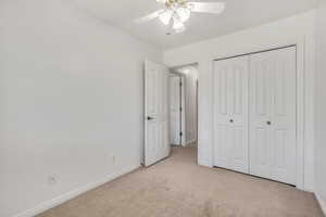 Unfurnished bedroom featuring light carpet, a ceiling fan, and a closet