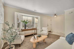 Living area featuring carpet flooring, crown molding, tile patterned flooring, and a textured ceiling