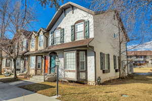 View of front facade with a front yard, stucco siding, and roof with shingles