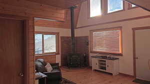 Living area with a wood stove, a vaulted wood ceiling, and light wood-style floors