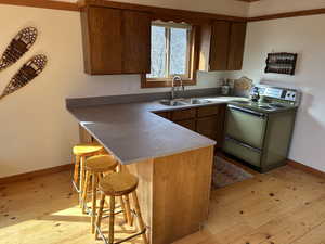 Kitchen with a breakfast bar, light wood-style floors, a peninsula, and range with electric cooktop
