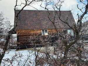 View of side of home with a shingled roof