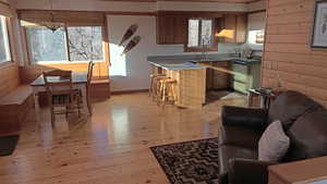 Kitchen featuring light wood-style floors, plenty of natural light, wooden walls, hanging light fixtures, and range with electric cooktop