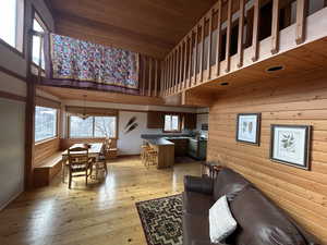 Living area featuring a high wood ceiling, wooden walls, and light wood-style floors