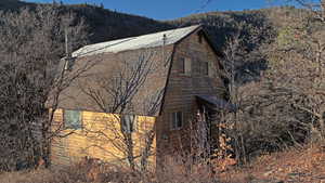 View of home's exterior with a shingled roof and a view of trees