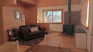 Living area with wood walls, light wood-style flooring, and a wood stove