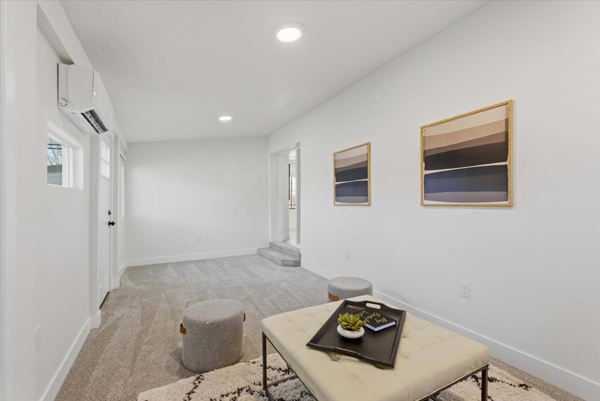 Hallway with light colored carpet, a wall mounted AC, and recessed lighting