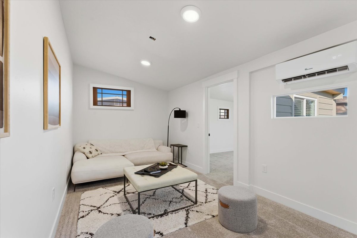 Carpeted living room featuring a wall mounted air conditioner, vaulted ceiling, and recessed lighting