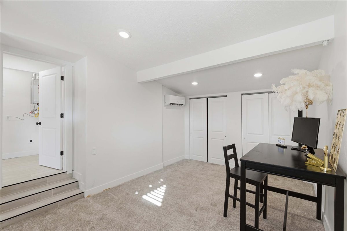 Dining room with an office area, light carpet, an AC wall unit, beam ceiling, and recessed lighting