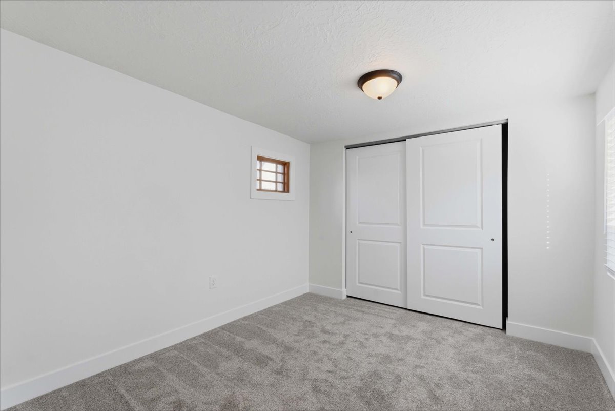 Unfurnished bedroom with light carpet, a closet, and a textured ceiling