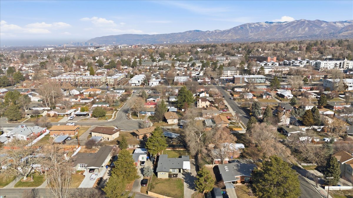 Aerial view of property and surrounding area featuring a mountainous background and nearby suburban area