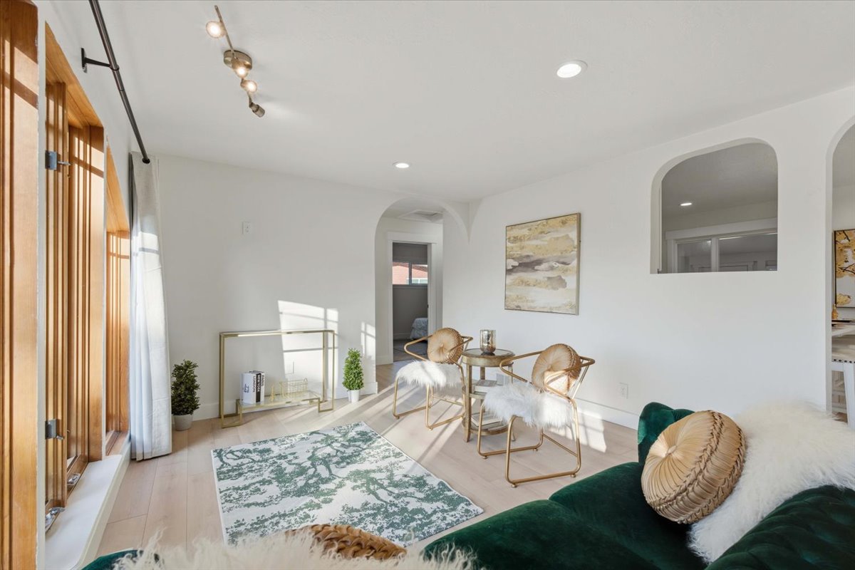 Living room with arched walkways, light wood finished floors, and recessed lighting