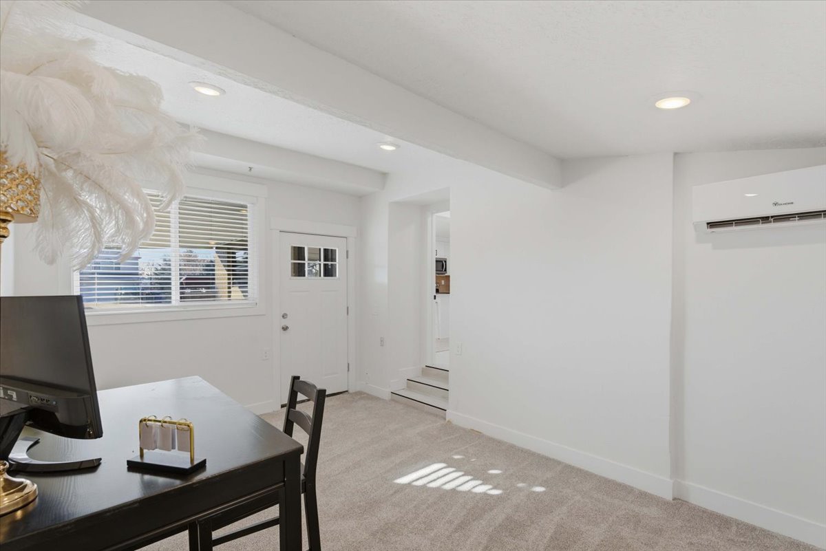 Office space featuring light carpet, an AC wall unit, and recessed lighting
