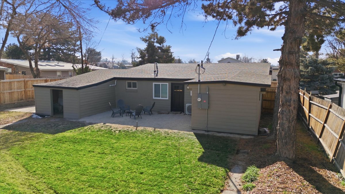Rear view of house featuring a fenced backyard, roof with shingles, a patio area, and an outbuilding