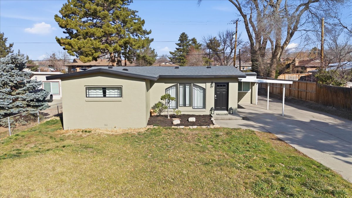 View of front of home featuring stucco siding, driveway, and a carport