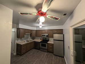 Kitchen featuring light countertops, stainless steel appliances, ceiling fan, dark wood-style floors, and dark brown cabinets