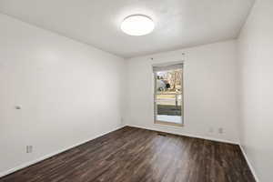 Empty room featuring a textured ceiling and dark wood-style floors
