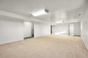 Empty room featuring a textured ceiling, light carpet, and stairway