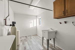 Laundry room with light wood finished floors, hookup for a washing machine, and a textured ceiling