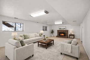 Living room featuring carpet, a fireplace, and a textured ceiling